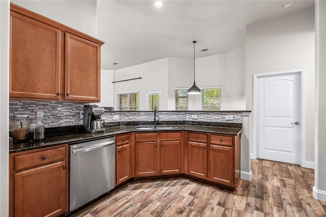 kitchen with tasteful backsplash, wood finished floors, dishwasher, a sink, and brown cabinets
