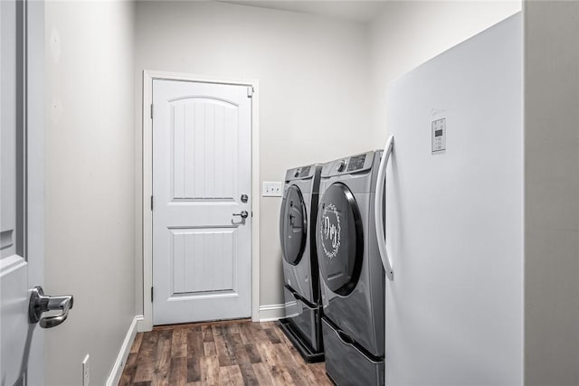 washroom with separate washer and dryer, laundry area, baseboards, and dark wood finished floors