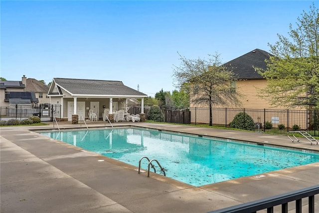 community pool with a patio area and fence