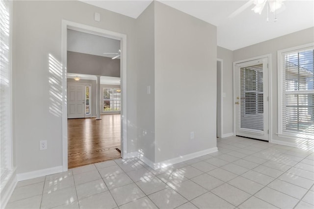 unfurnished room with light tile patterned floors, ceiling fan, plenty of natural light, and baseboards