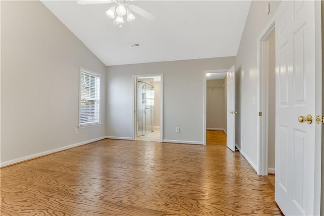 unfurnished bedroom featuring light wood-type flooring, baseboards, a walk in closet, visible vents, and lofted ceiling