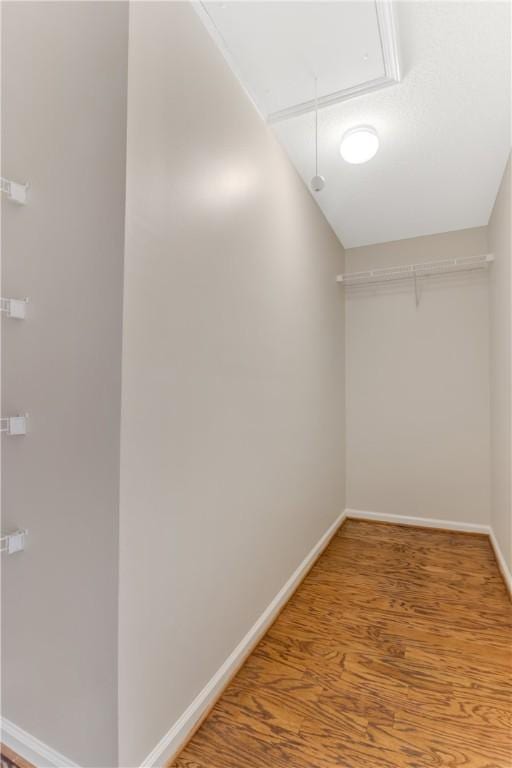 walk in closet featuring attic access and wood finished floors