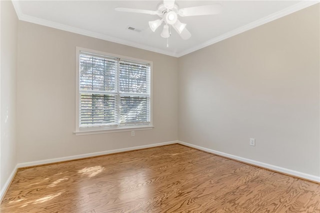 spare room featuring visible vents, baseboards, ornamental molding, a ceiling fan, and wood finished floors
