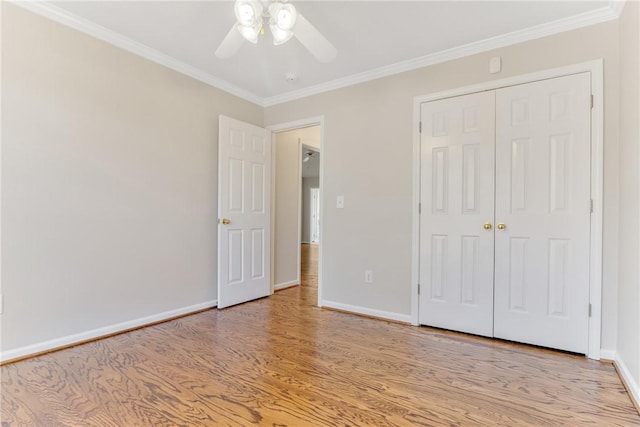 unfurnished bedroom with a closet, light wood-style flooring, baseboards, and crown molding