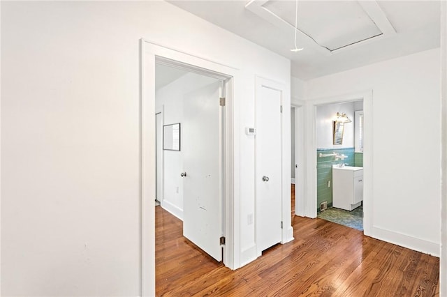 hallway featuring tile walls, attic access, and wood finished floors