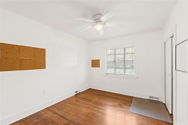 unfurnished room featuring ceiling fan, visible vents, baseboards, and wood finished floors