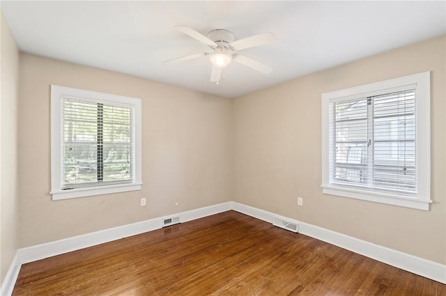 spare room with visible vents, baseboards, and dark wood finished floors