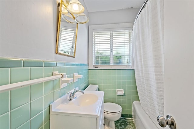 full bathroom featuring vanity, toilet, wainscoting, shower / bath combo with shower curtain, and tile walls