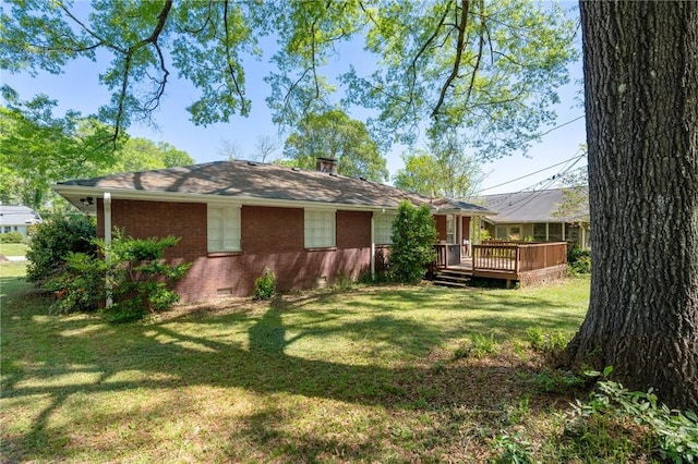 exterior space with a chimney, crawl space, brick siding, a wooden deck, and a yard