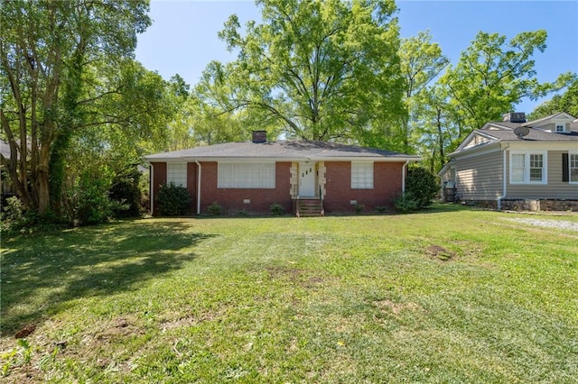 ranch-style home featuring brick siding, entry steps, a chimney, and a front lawn