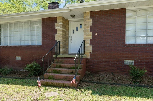 entrance to property featuring crawl space, a chimney, and brick siding