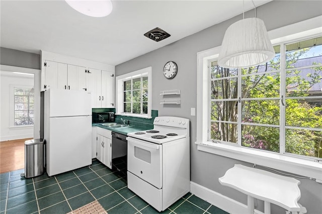 kitchen featuring baseboards, a sink, dark tile patterned floors, white appliances, and white cabinetry