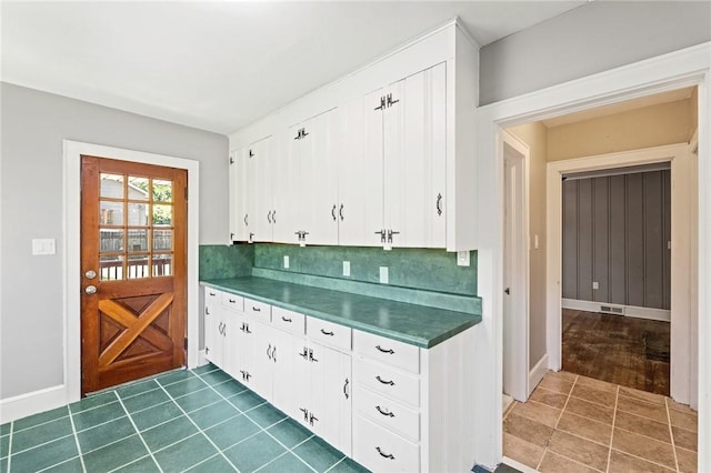 kitchen featuring backsplash, white cabinets, and dark tile patterned flooring