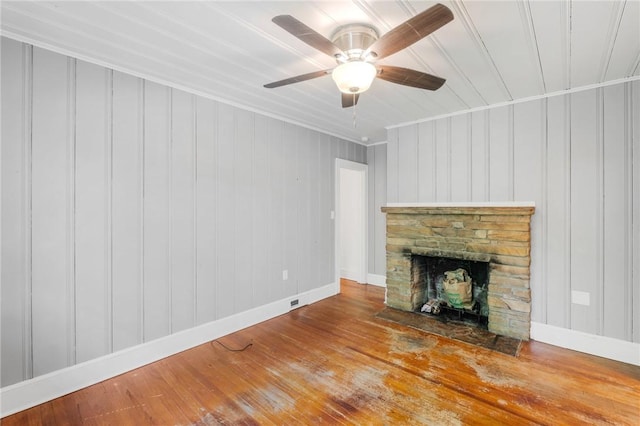 unfurnished living room featuring baseboards, ornamental molding, a ceiling fan, a fireplace, and wood finished floors