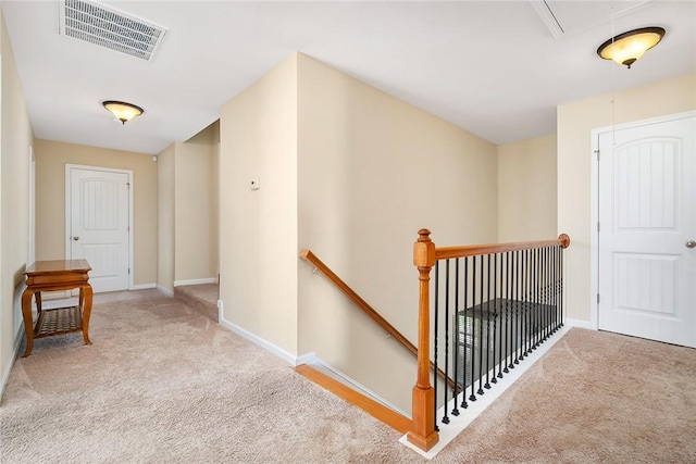 hallway with baseboards, an upstairs landing, attic access, visible vents, and carpet