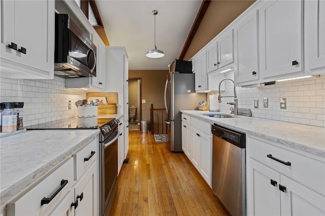 kitchen featuring light wood-type flooring, appliances with stainless steel finishes, white cabinetry, and a sink