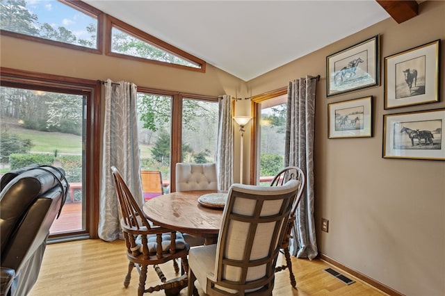 dining space with light wood-style floors, visible vents, baseboards, and lofted ceiling