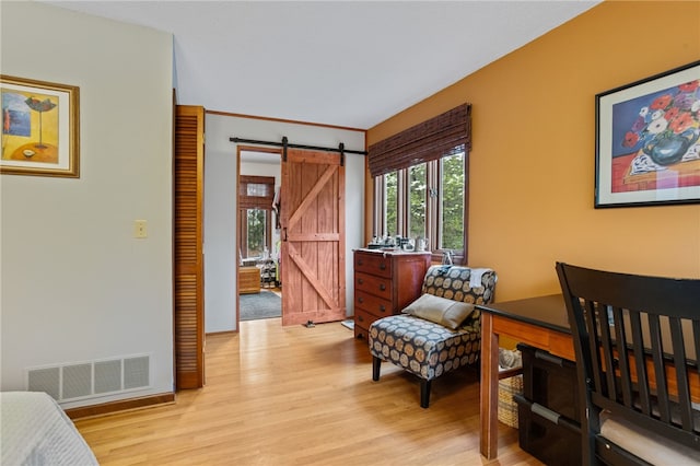 living area featuring light wood-style floors, a barn door, visible vents, and baseboards