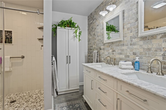 bathroom featuring wood finished floors, a sink, double vanity, and tiled shower