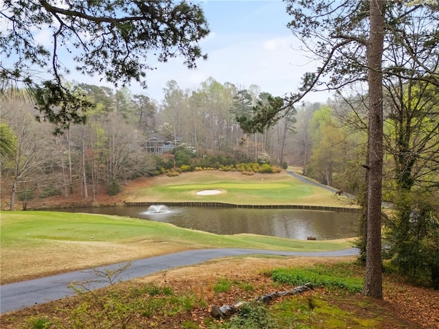 view of property's community featuring a lawn, view of golf course, and a water view