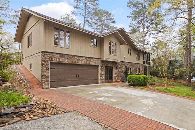 view of front of house featuring concrete driveway, stone siding, and an attached garage