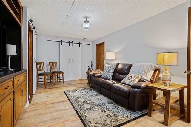 living room with a barn door and light wood finished floors