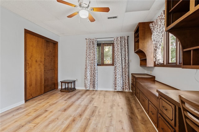 interior space featuring baseboards, visible vents, light wood-type flooring, and a ceiling fan