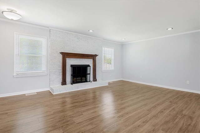 unfurnished living room with wood finished floors, visible vents, crown molding, and a brick fireplace