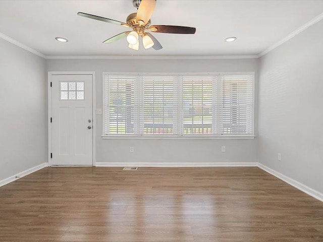 foyer with crown molding, a ceiling fan, visible vents, and wood finished floors