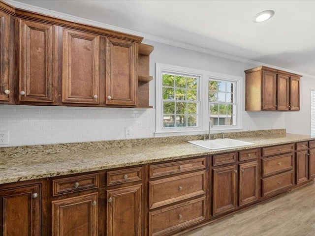 kitchen featuring decorative backsplash, open shelves, crown molding, a sink, and light wood-type flooring