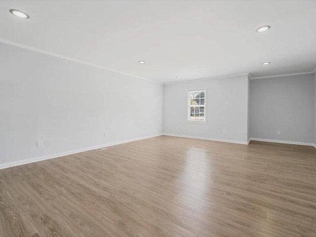 empty room featuring wood finished floors, crown molding, recessed lighting, and baseboards