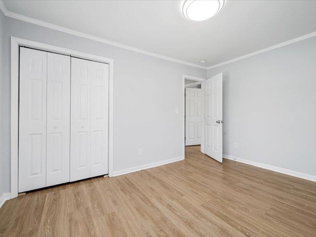 unfurnished bedroom with baseboards, light wood-type flooring, ornamental molding, and a closet