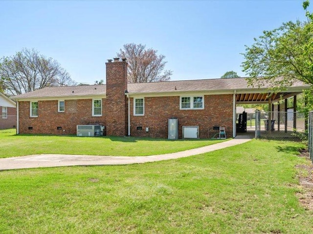 back of property with crawl space, a yard, a chimney, brick siding, and fence