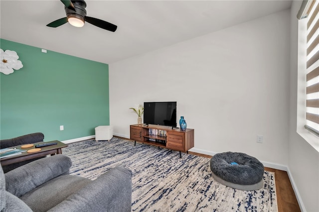 living area with ceiling fan, wood finished floors, and baseboards