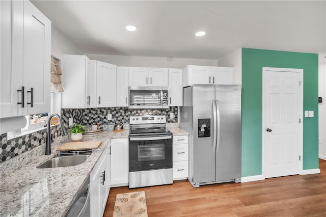 kitchen featuring a sink, white cabinets, light wood-style flooring, and stainless steel appliances