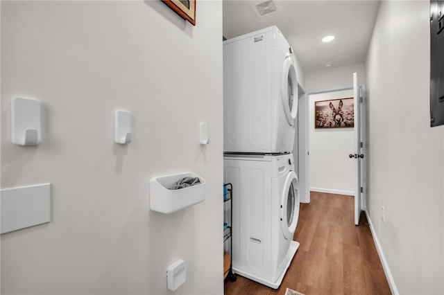 laundry room featuring laundry area, visible vents, wood finished floors, baseboards, and stacked washer / drying machine