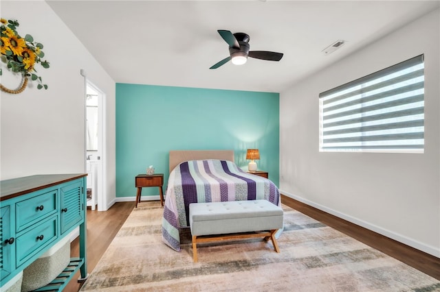 bedroom featuring ceiling fan, visible vents, baseboards, and wood finished floors