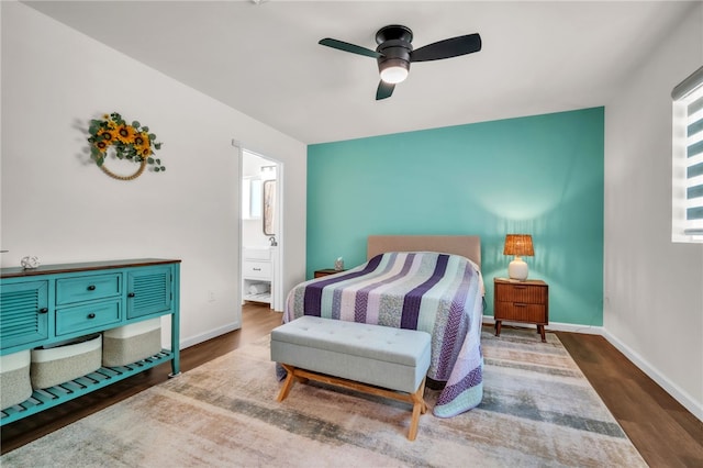 bedroom with wood finished floors, ceiling fan, baseboards, and connected bathroom