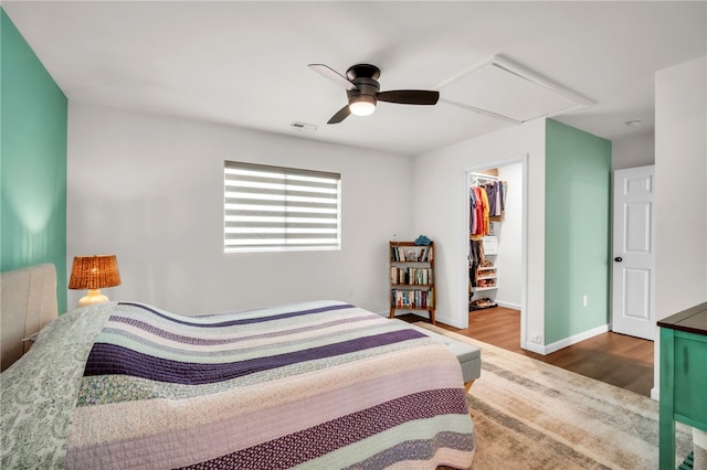 bedroom featuring a closet, attic access, a walk in closet, visible vents, and wood finished floors