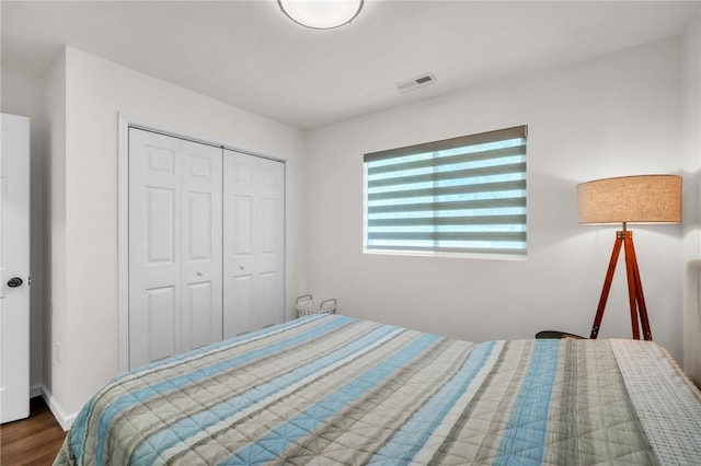 bedroom featuring visible vents, a closet, baseboards, and wood finished floors