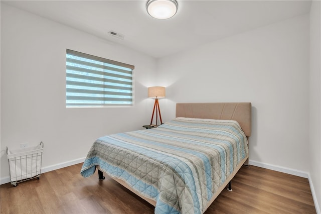 bedroom featuring visible vents, baseboards, and wood finished floors