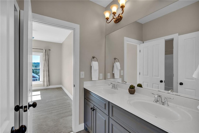 full bath with baseboards, a chandelier, a sink, and double vanity