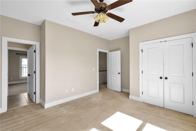unfurnished bedroom with baseboards, a closet, and light colored carpet