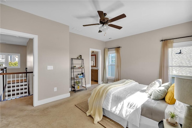 bedroom with light carpet, ensuite bathroom, visible vents, baseboards, and ceiling fan