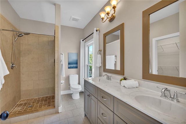 bathroom featuring a tile shower, toilet, tile patterned flooring, and a sink