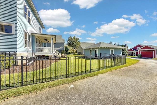 view of home's exterior with a fenced front yard, a lawn, a ceiling fan, a porch, and a garage