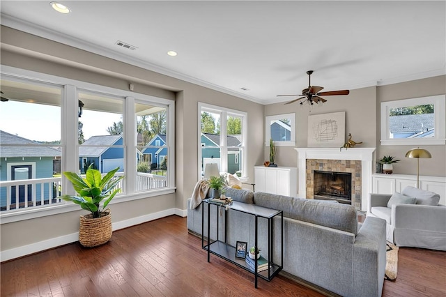 living room with baseboards, visible vents, ceiling fan, crown molding, and a fireplace