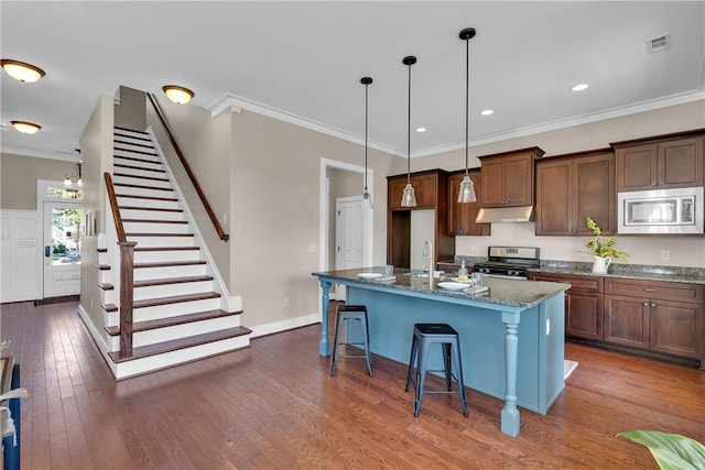 kitchen featuring dark stone counters, crown molding, appliances with stainless steel finishes, under cabinet range hood, and visible vents