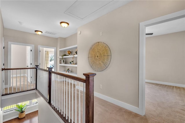 corridor with carpet floors, visible vents, baseboards, and an upstairs landing