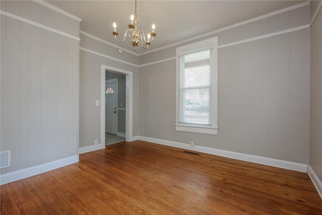empty room with crown molding, baseboards, a chandelier, and wood finished floors
